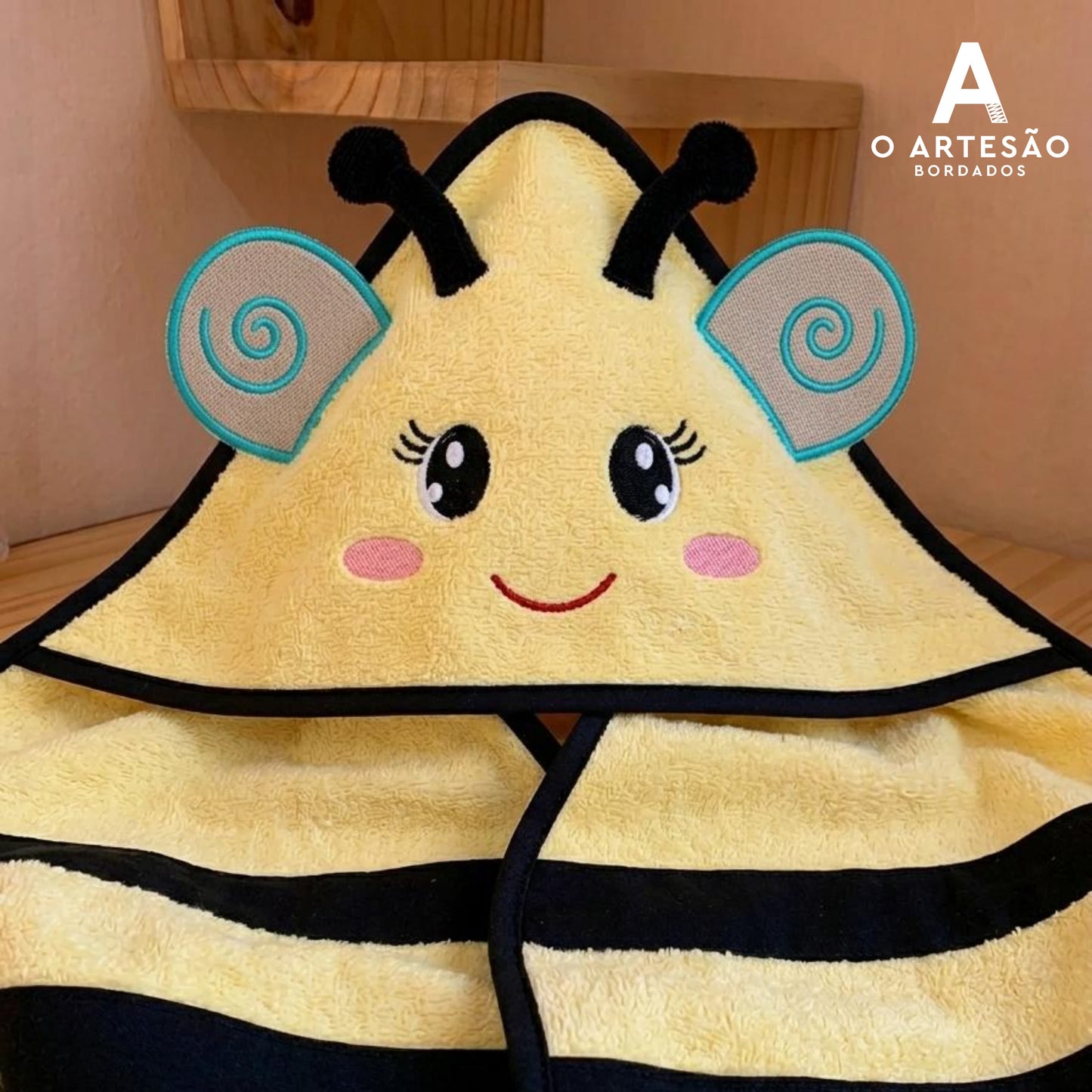 Toalha com Capuz com Matriz de Bordado Abelhinha Rostinho Lúdico com fundo simples bege